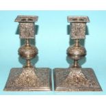 A pair of Victorian short silver candlesticks of square form having a knopped stem, with embossed