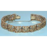 A 9ct gold bracelet c1970's of thirteen pierced and textured plaques of abstract design, with
