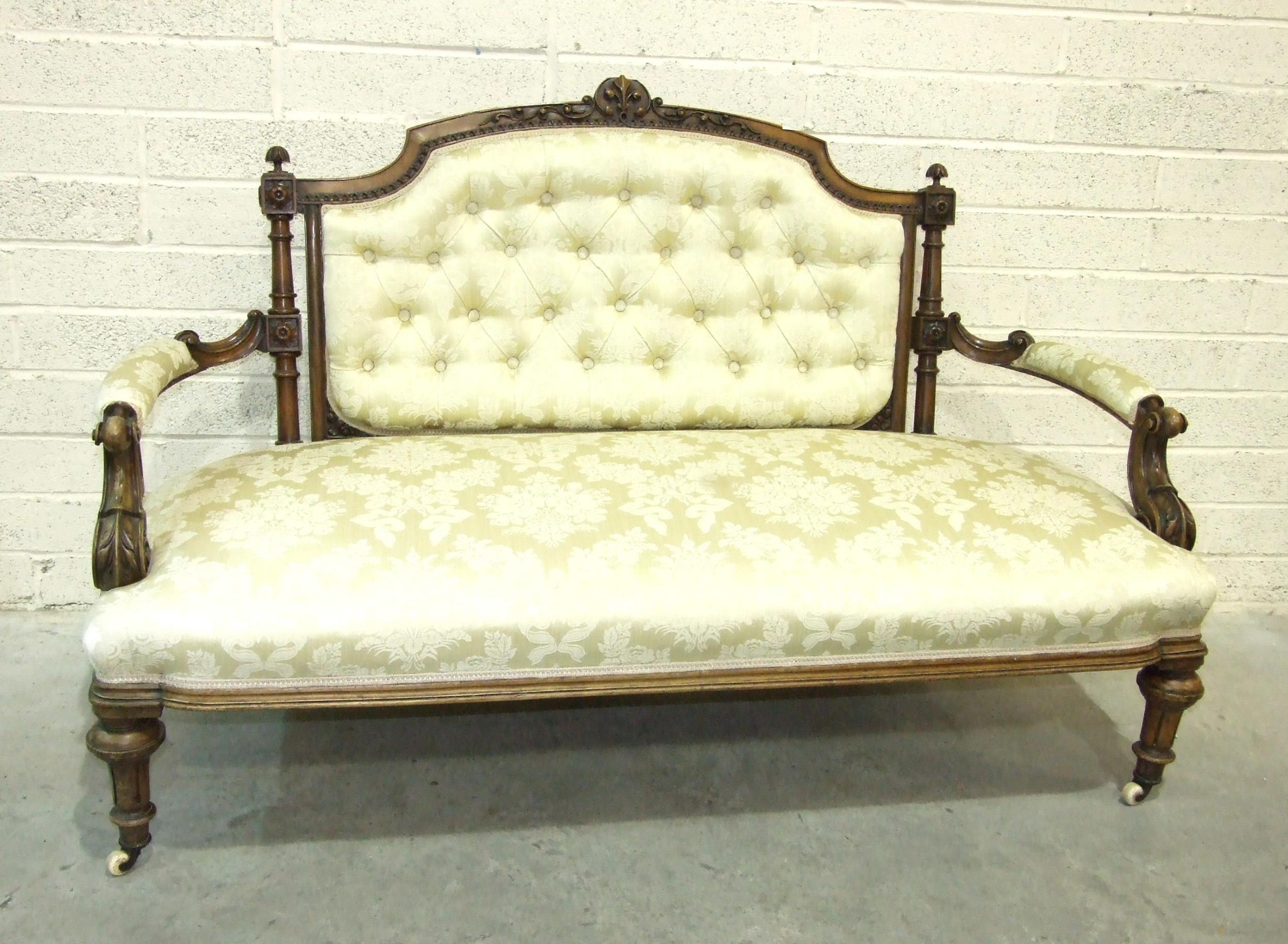 A late-Victorian walnut drawing room settee, the carved and upholstered back to scroll open arms and