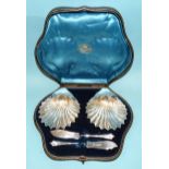 A pair of silver shell-shaped butter dishes, 12 x 10cm, with knives, in fitted case, Goldsmiths &