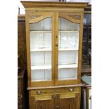 A tall pine dresser, the moulded cornice above a pair of glazed doors, with waist drawer and two