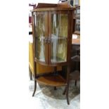 An Edwardian inlaid mahogany low corner bow-fronted display cabinet having a pair of glazed doors,