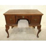 An 18th century walnut feather-banded lowboy, having a central drawer and two small cupboards, on
