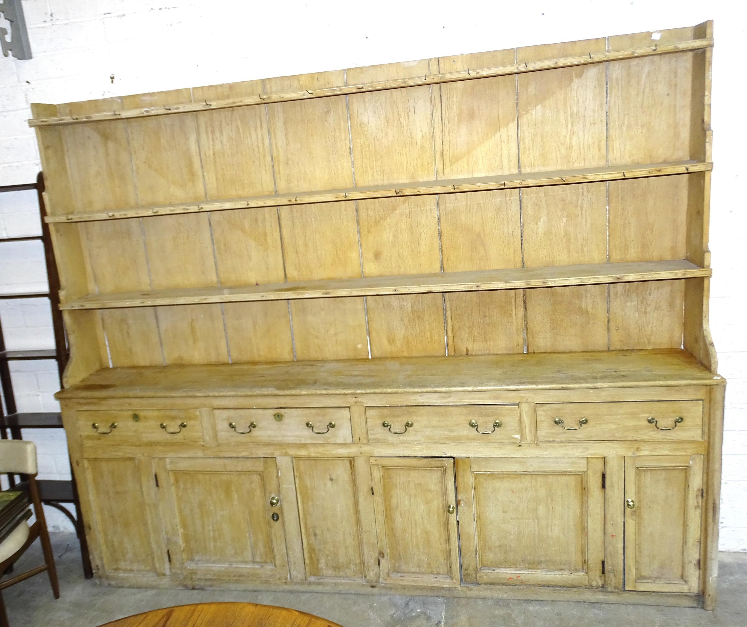 A Victorian pine kitchen dresser, the reduced plate rack with three shelves, the base with four