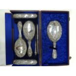 A cased seven-piece silver-mounted dressing table set embossed with flowers with etched letter '