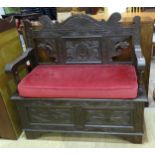 A carved oak hall seat with hinged seat, 104cm wide, 100cm high, 41cm deep.