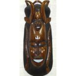 A carved wood tribal mask in the form of two faces, with carved snake decoration, 90cm.