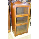 A walnut three-tier bookcase with glazed up-and-over doors, 87cm wide, 150cm high.