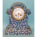 A ceramic mantel clock decorated with enamelled flower heads and leaves, the white enamel dial