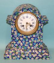 A ceramic mantel clock decorated with enamelled flower heads and leaves, the white enamel dial