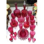 A cranberry glass decanter, 27cm high, a circular frilled bowl and a collection of cranberry glasses