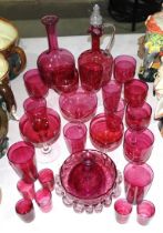 A cranberry glass decanter, 27cm high, a circular frilled bowl and a collection of cranberry glasses