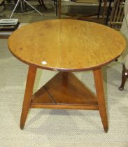 A stained pine circular 'cricket' table, on three splayed legs joined by a triangular undertier,