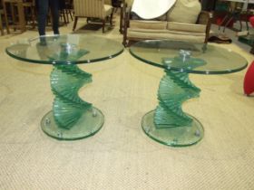 A pair of contemporary circular glass-topped occasional tables on stepped spiral bases, in the