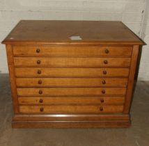 An Edwardian oak plan chest of seven drop-down-fronted drawers, on plinth base and panelled back,