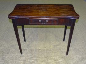 A George III mahogany serpentine-shaped fold-over card table with frieze drawer, on square moulded