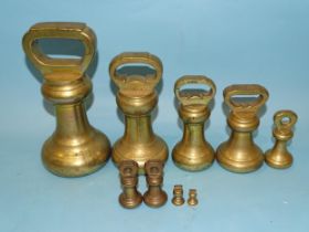 A collection of graduated brass bell-shaped weights, the largest 7lbs and stamped Avery Ltd.