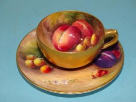 A Royal Worcester cabinet cup and saucer decorated with fruit on a naturalistic ground, signed