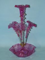 A late-19th century cranberry glass epergne, the central trumpet vase flanked by three further