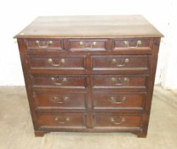 An antique oak rectangular chest having an arrangement of eleven small drawers of varying size,