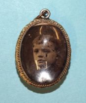 An oval double-sided locket with two tin-type photographs.