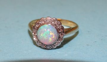 An opal and diamond cluster ring set a round opal within a border of sixteen 8/8-cut diamonds, in