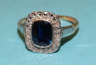 An Edwardian sapphire and diamond cluster ring, the cushion-cut sapphire within a border of nineteen