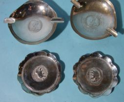 Two Indian white metal ashtrays and two others marked Sterling Silver, each with a one-rupee coin at