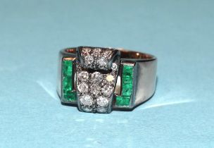 An Art Deco ring with diamond-set scroll between two lines of emerald baguettes, in unmarked gold