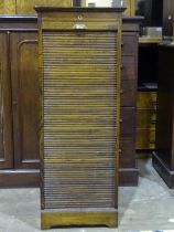 A 20th century tambour-fronted stained wood filing cabinet, the door enclosing nine filing slides,