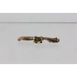 Floral bar brooch set with a green paste stone, set in yellow meta; with a partial 9ct stamp,