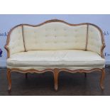 A carved walnut framed two seater settee, upholstered in a cream fabric, button back raised on