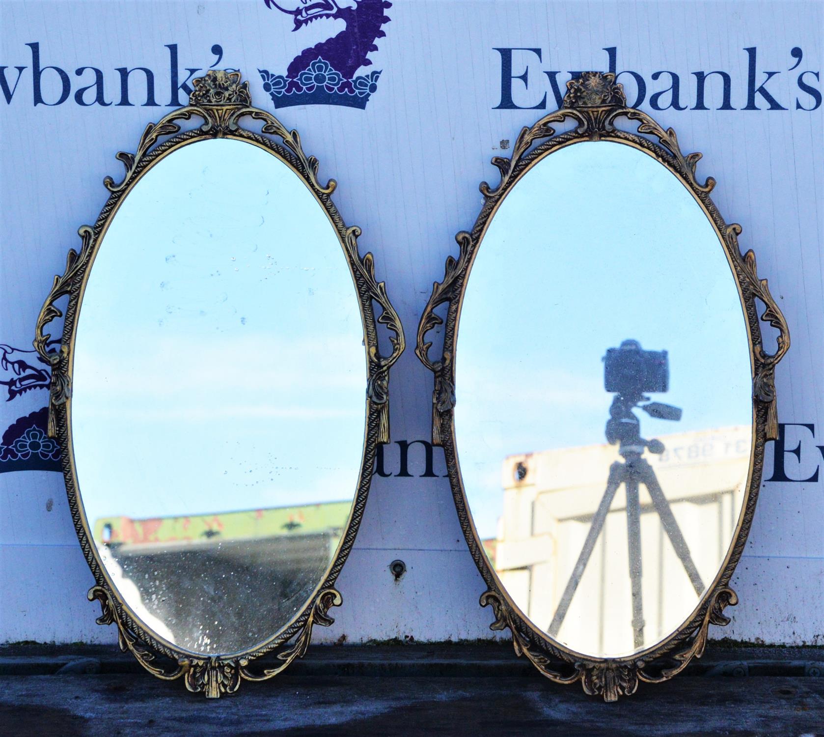 Pair of gilt metal wall mirrors, the oval plates with foliate scroll frames surmounted by baskets