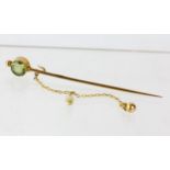 Peridot set stick pin brooch with ball and safety chain, in tested 14ct, length 60mm, 1.6 grams