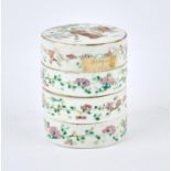 A famille rose, three tiered box of cylindrical form, decorated on the top with Manchu/Chinese