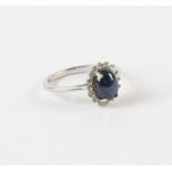 A star sapphire and paste cluster ring, central oval cabochon cut star sapphire with a surround of