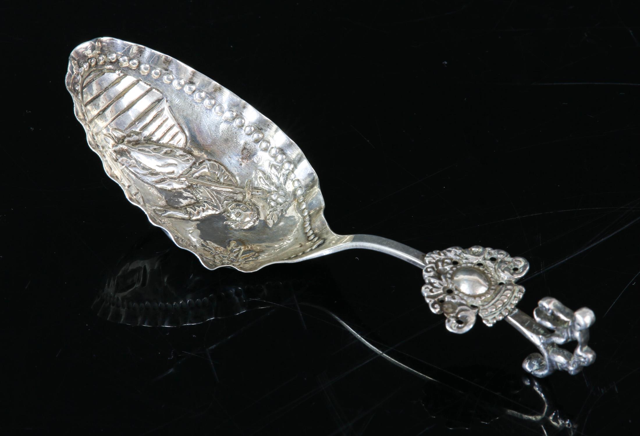 Silver baptismal spoon with embossed figure of a person carrying a cross, import Chester 1904.