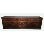 A Country House oak dresser base, mid 18th Century, the two plank top above a central flank of