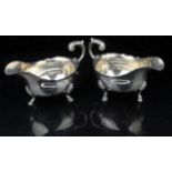 A pair of George III sauce boats with flared rims, and foliate scroll handle on three hoof feet,