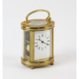 A brass oval form carriage clock, with white enamel dial with Roman numeral chapter ring,