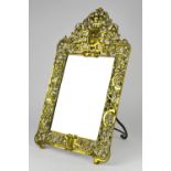 A pierced brass easel framed mirror, decorated with a bearded man to the cresting,