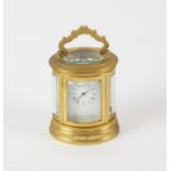 A miniature French brass oval carriage clock, the white enamel dial with Roman numeral chapter ring,