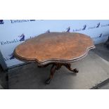Victorian walnut table, the shaped top with carved edge of trailing clover, on as bulbous support