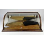 A mahogany and glass display case, late 19th Century, with curving glass top, mirrored door and