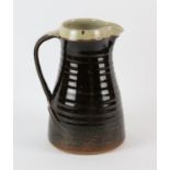 LEACH POTTERY, a tenmoku glazed pottery jug, with impressed marks, 23cm high Note: This pottery jug