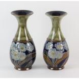 ROYAL DOULTON, a pair of vases decorated with tube lined flowers by Emily J Partington, 22cm high,