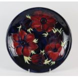MOORCROFT, an Anemone design plate with pink and mauve coloured flowers on a blue background,