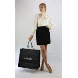 A CHANEL BOUTIQUE classic black wool, black silk-lined mini skirt with silk-lined hip pockets fits