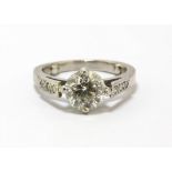 Single stone diamond ring with diamond set shoulders, central round brilliant cut diamond,