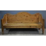 Rectangular pine settle, 19th Century, with shaped cresting rail and arms, solid back and seat.